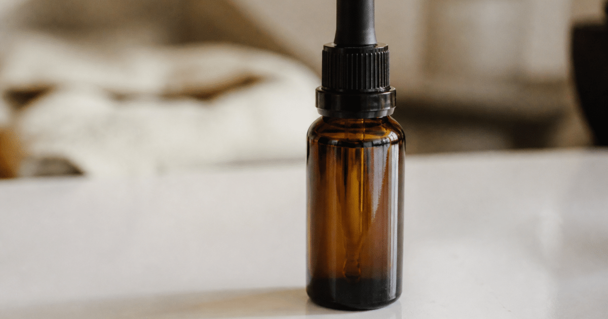 Bouteille de liquide CBD posee sur surface blanche brillante
