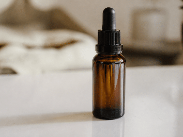 Bouteille de liquide CBD posee sur surface blanche brillante