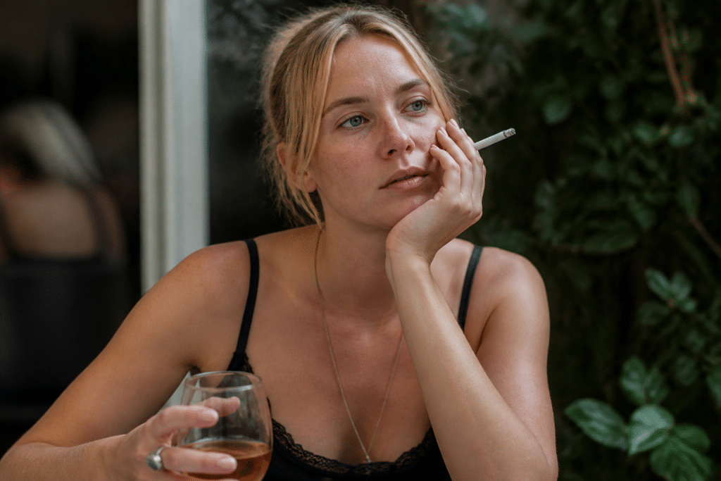 Femme touchant son visage avec cigarette et verre d'alcool