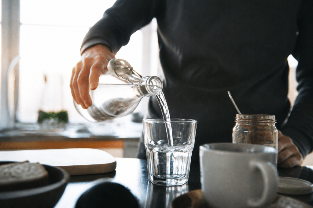 Personne versant liquide dans verre transparent le matin