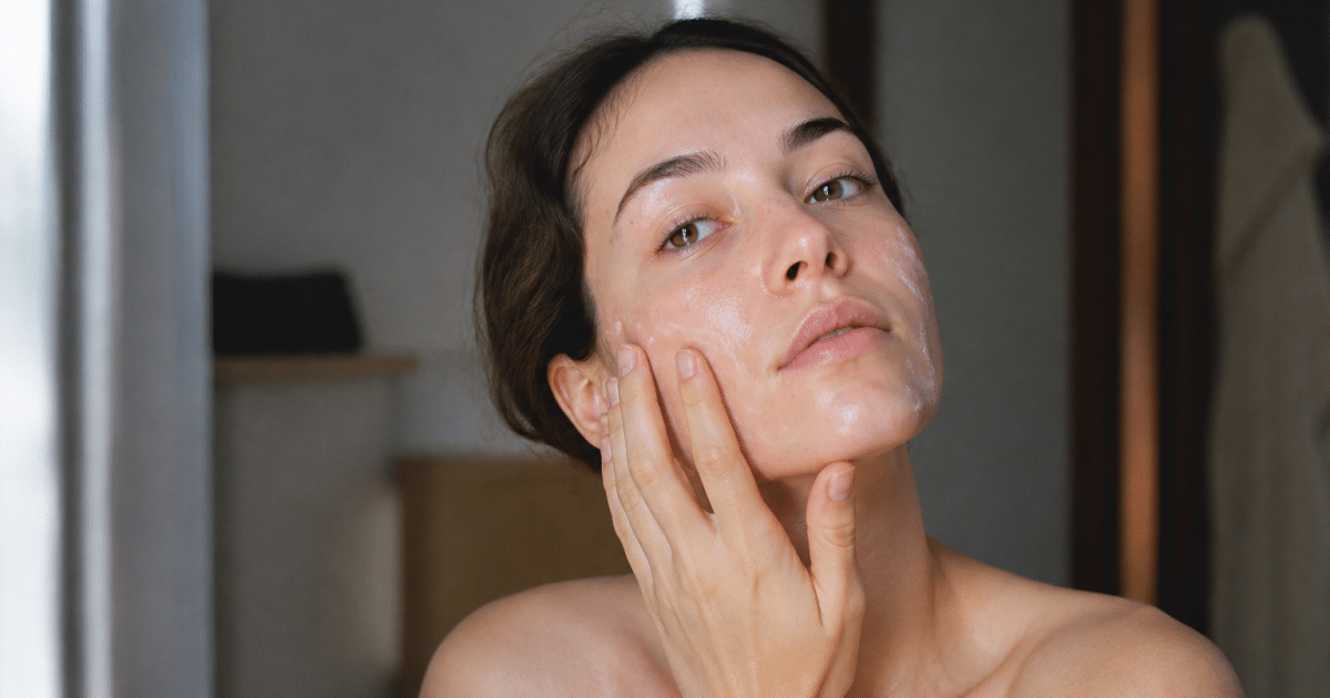 Femme appliquant creme visage avec doigts, peau brillante lisse