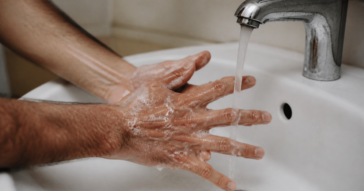 Mains lavees avec savon sous eau courante, doigts etales