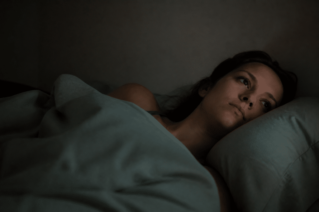 Personne allongee eveille dans lit sombre la nuit