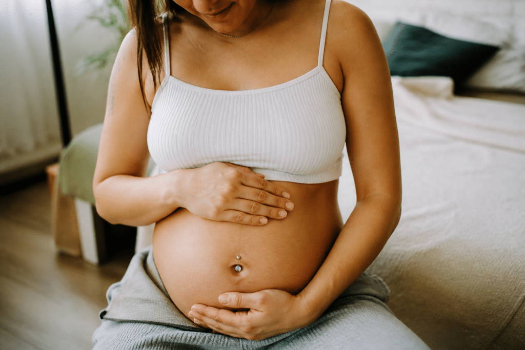 Femme enceinte touchant son ventre avec piercing au nombril visible
