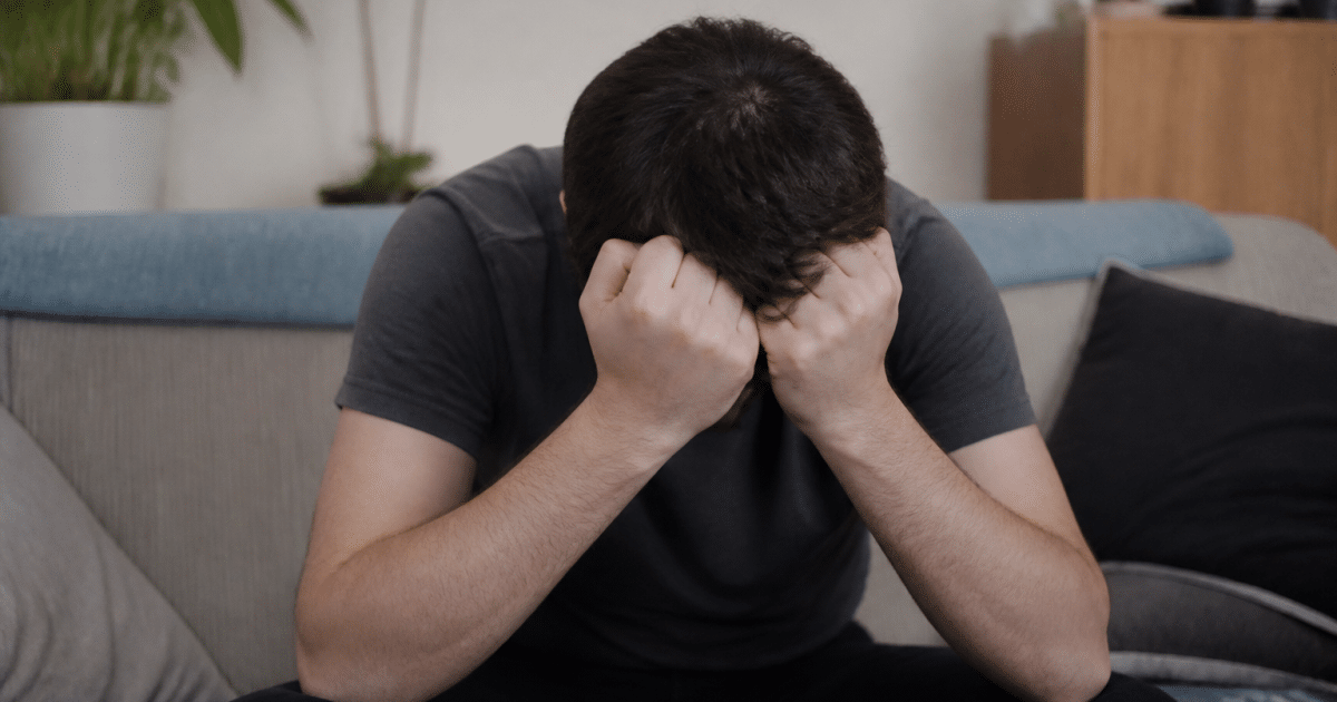 Personne assise tenant sa tete entre ses mains fermees