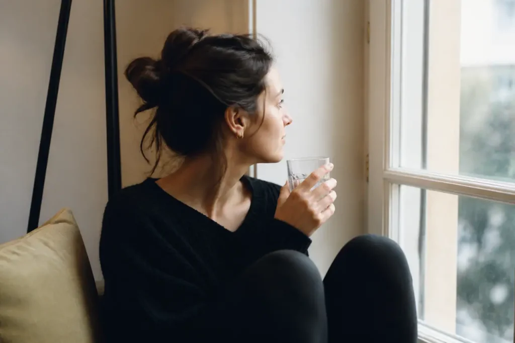 Femme assise pres de la fenetre tenant un verre