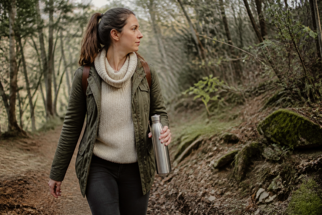 Femme avec gourde marchant sur un sentier forestier
