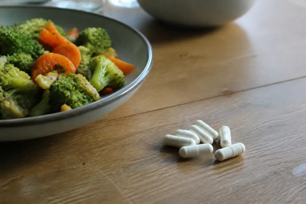 Gelules de magnesium posees pres d'une assiette de legumes