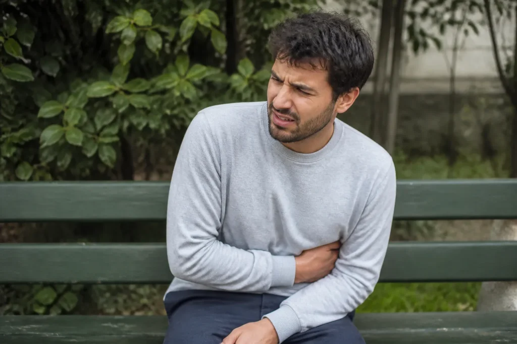 Homme assis serrant son flanc droit sur un banc