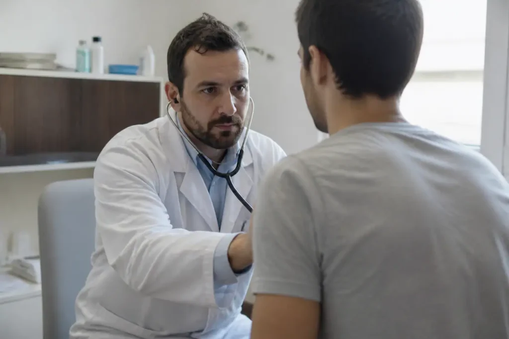 Medecin en blouse blanche examinant un patient au cabinet