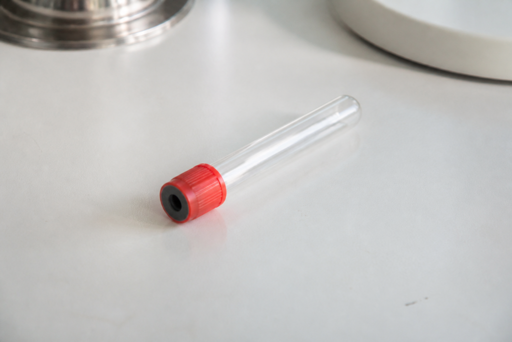 Tube rouge de prise de sang sur bureau blanc